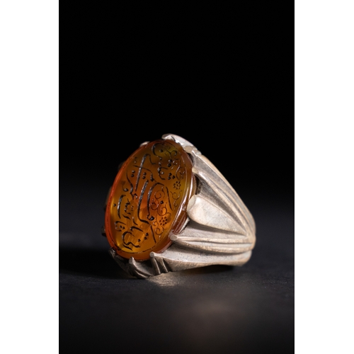 57 - An Islamic Silver Ring with Inscribed Amber-Toned Agate.

A silver ring set with an oval agate stone... 
