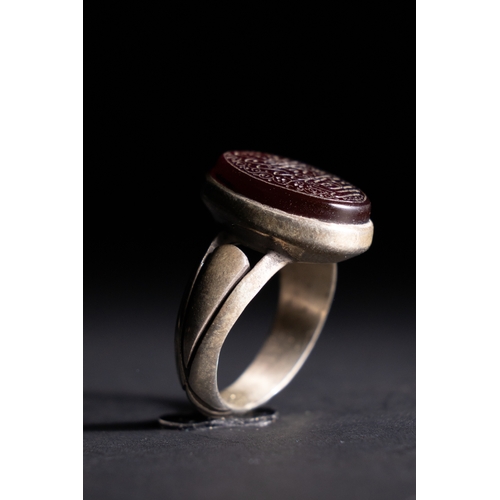 60 - An Islamic Silver Ring with Inscribed Red Agate.

A silver ring set with an oval red agate stone, en... 