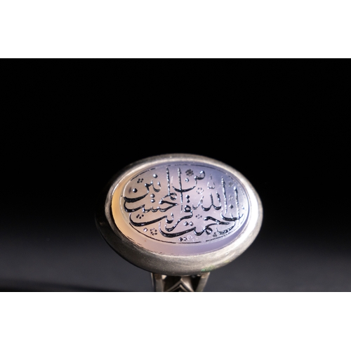 61 - An Islamic Silver Ring with Inscribed Lavender Agate.

A silver ring featuring an oval lavender agat... 