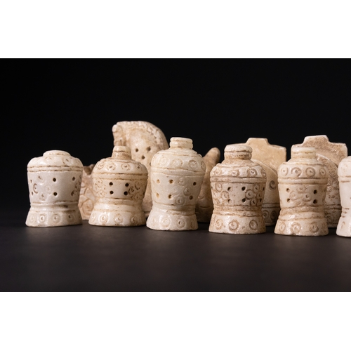 31 - A Complete Stone Half Chess Set, 19th Century.

A complete carved stone half chess set comprising si... 