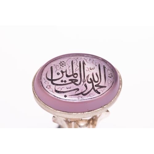 47 - An Islamic Silver Ring Set with a Carved Pink Agate Panel Featuring Arabic Calligraphy.

An Islamic ... 
