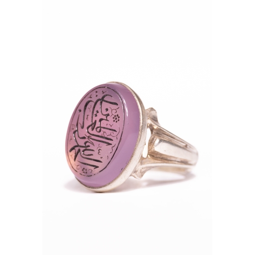 47 - An Islamic Silver Ring Set with a Carved Pink Agate Panel Featuring Arabic Calligraphy.

An Islamic ... 