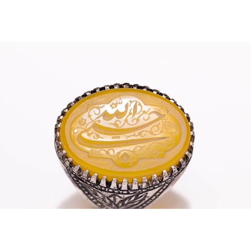 49 - An Islamic Silver Ring Set with a Carved Yellow Agate Panel Featuring Arabic Calligraphy.

An Islami... 