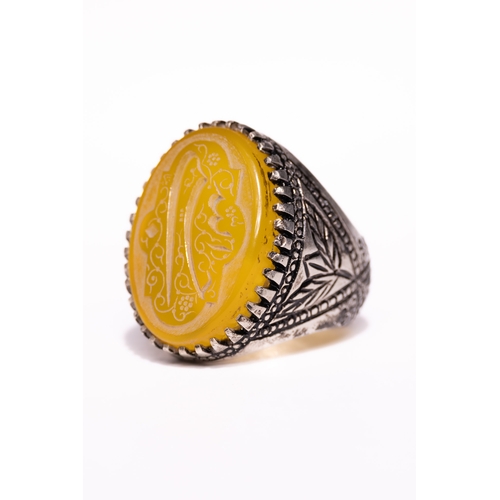 49 - An Islamic Silver Ring Set with a Carved Yellow Agate Panel Featuring Arabic Calligraphy.

An Islami... 
