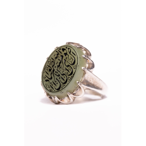 51 - An Islamic Silver Ring Set with a Carved Pale Green Agate Panel Featuring Arabic Inscription.

An Is... 