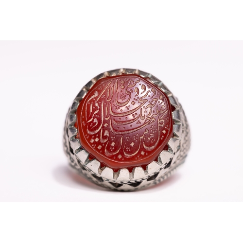 52 - An Islamic Silver Ring Set with a Carved Red Agate Panel Featuring Arabic Inscription.

An Islamic s... 