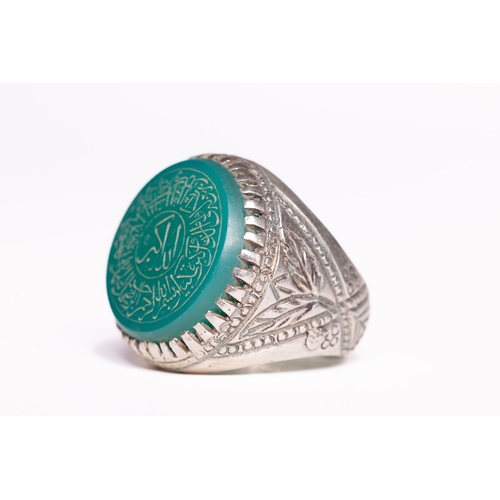 53 - An Islamic Silver Ring Set with a Carved Green Agate Panel Featuring Arabic Inscription.

An Islamic... 