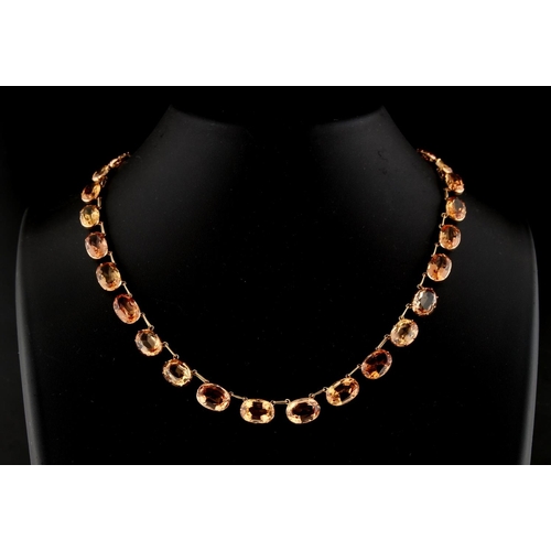 202 - A late Georgian topaz riviere necklace, the thirty graduated topaz collets weighing an estimated tot... 