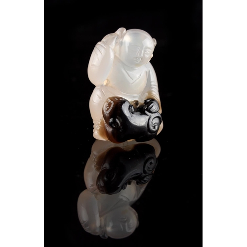 280 - A Chinese carved agate figure of a seated boy with a cub at his feet, 1.35ins. (3.4cms.) high (see i... 