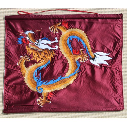 99 - An embroidered silk wall hanging depicting a dragon on a burgundy ground, 26 by 31ins. (66 by 78cms.... 