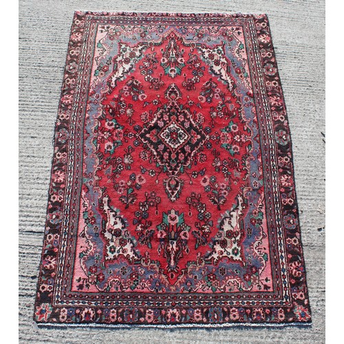 381 - A Hamadan woollen hand-made rug with red ground, 106 by 71ins. (270 by 180cms.).