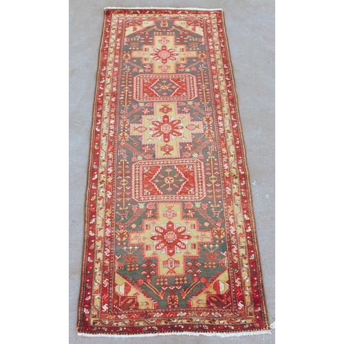 382 - A Kordi woollen hand-made rug with red ground, 132 by 50ins. (335 by 127cms.).