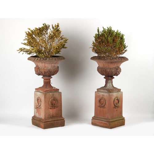 533 - Property of a gentleman - a pair of well weathered terracotta garden urns on separate plinths, with ... 