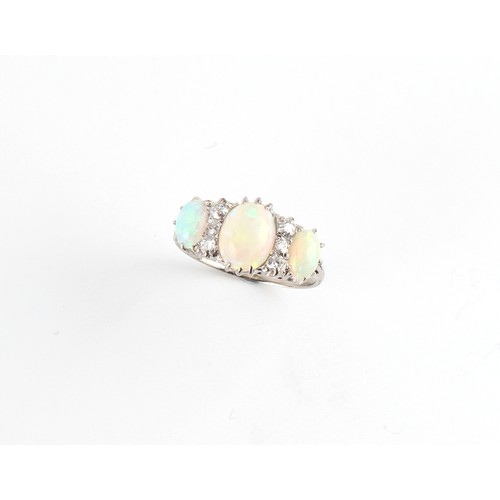 123 - A white gold opal & diamond ring, the three oval opals alternating with two rows of three round cut ... 