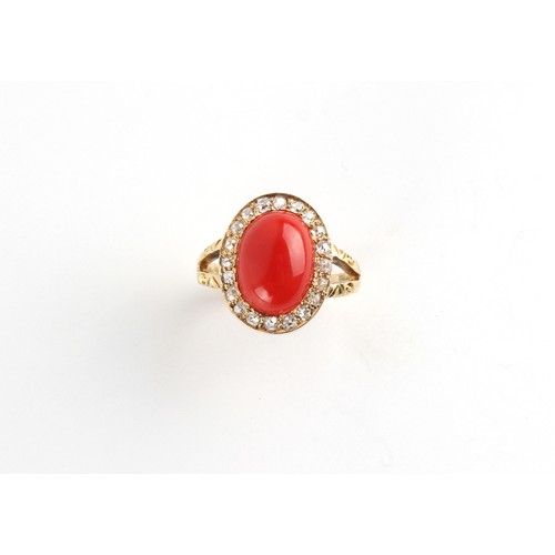 106 - An unmarked yellow gold coral & diamond ring, the oval cabochon coral measuring approximately 19 by ... 