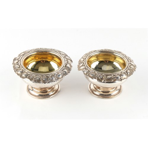 262 - Property of a gentleman - a pair of William IV silver circular pedestal salts with vine borders & gi... 