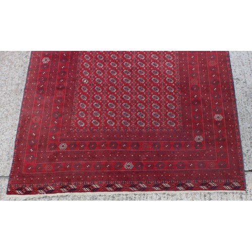 285 - Property of a gentleman - a Turkoman hand-knotted wool rug with red ground, 116 by 80ins. (295 by 20... 