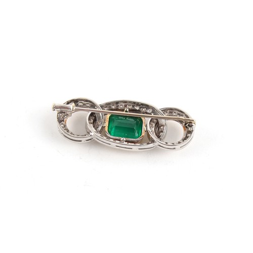 92 - An unmarked white & yellow gold emerald & diamond interlinking loops brooch, the emerald weighing ap... 