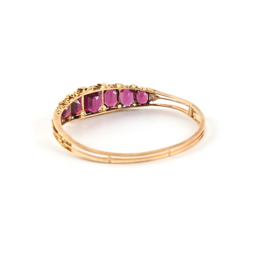 133 - A late Victorian unmarked gold garnet & diamond hinged bangle, set with seven graduated emerald cut ... 