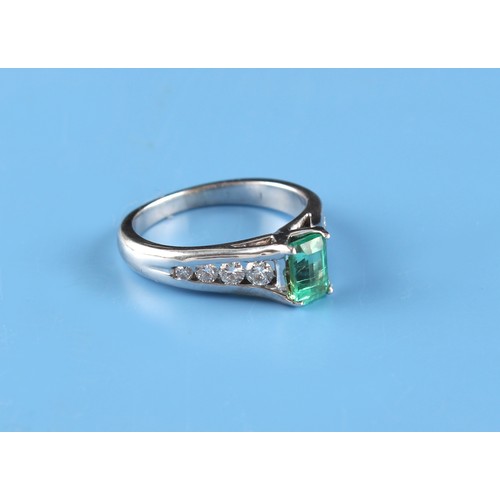 135 - An unmarked white gold or platinum emerald & diamond ring, the rectangular cut emerald weighing appr... 