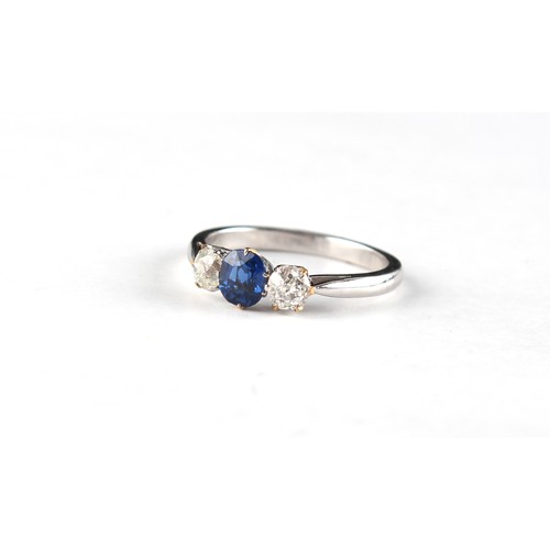 146 - An unmarked white gold sapphire & diamond three stone ring, the oval cut sapphire weighing approxima... 