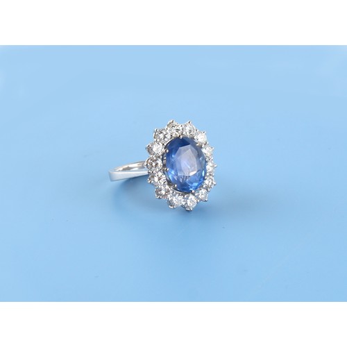 125 - An 18ct white gold sapphire & diamond oval cluster ring, the large oval cushion cut cornflower blue ... 