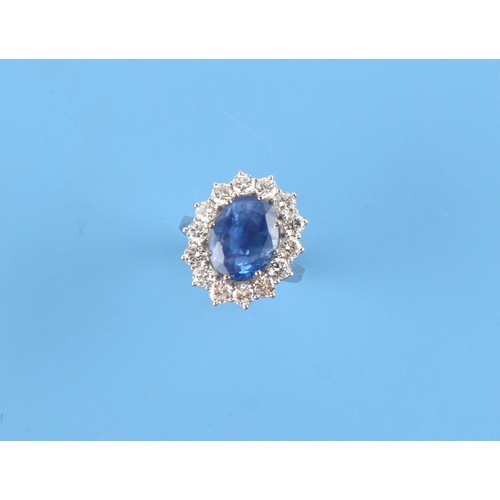 125 - An 18ct white gold sapphire & diamond oval cluster ring, the large oval cushion cut cornflower blue ... 