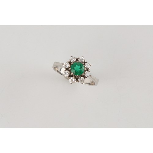 121 - An 18ct white gold emerald & diamond cluster ring, the round cut emerald weighing approximately 0.59... 