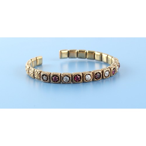 167 - An unmarked 9ct gold ruby & diamond torc bangle, set with five round cut rubies alternating with six... 