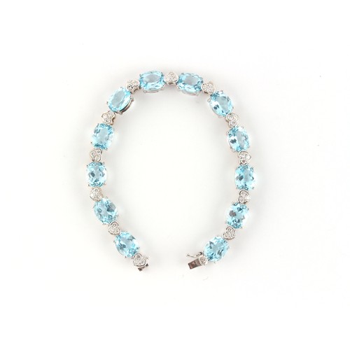 173 - An 18ct white gold blue topaz & diamond bracelet, with twelve oval cut blue topaz alternating with h... 