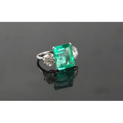 103 - A fine white gold emerald & diamond three stone ring, the large rectangular cut emerald weighing app... 