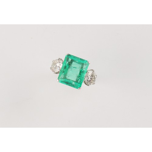 103 - A fine white gold emerald & diamond three stone ring, the large rectangular cut emerald weighing app... 