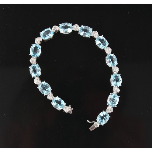 40 - An 18ct white gold blue topaz & diamond bracelet, with twelve oval cut blue topaz alternating with h... 