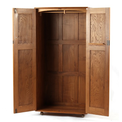 234 - Property of a deceased estate - an Ercol elm two-door wardrobe, enclosing a hanging rail, on castors... 