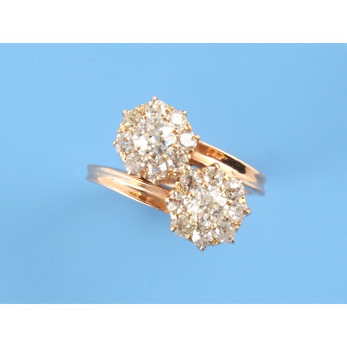 91 - An unmarked Continental yellow gold diamond twin cluster crossover ring, the estimated total diamond... 