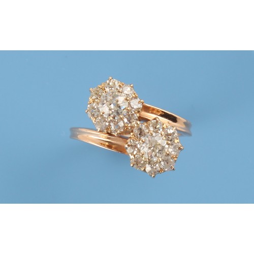91 - An unmarked Continental yellow gold diamond twin cluster crossover ring, the estimated total diamond... 