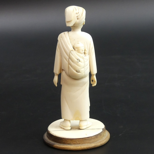 179 - Finely carved Indian ivory figure of a man carrying a child on his back, circa 1900. 145mm tall.