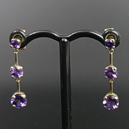 19 - A pair of 9ct gold 3 graduated amethyst drop earrings. 1.4 grams. 23mm long. Bottom stones are 5mm i... 