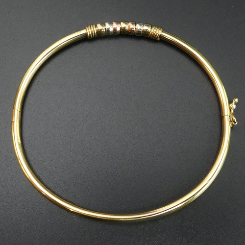 38 - 9 carat gold hinged bangle with 3 colour gold rings embellishment. 5.3 grams. 2.7mm and 4.3 mm wide.... 