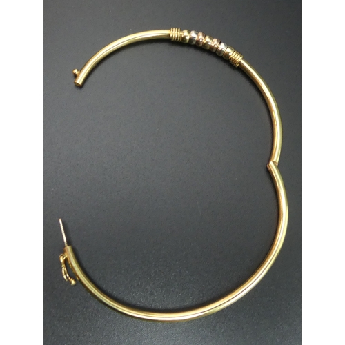 38 - 9 carat gold hinged bangle with 3 colour gold rings embellishment. 5.3 grams. 2.7mm and 4.3 mm wide.... 