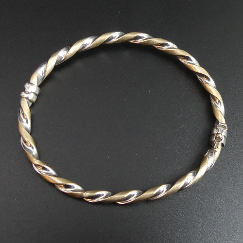 58 - 9ct white and yellow gold twisted design hinged bangle. 4.9 grams. 4.2mm wide.
UK Postage £10.