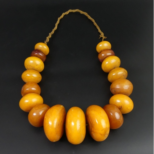 78 - African butterscotch amber copal bead necklace. 594 grams. 68 cm in length. Largest bead 6 cm.
UK Po... 