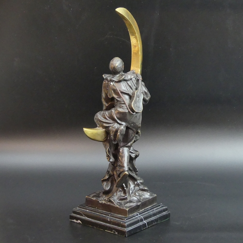 124 - A bronze figure of a Pierrot ascending a crescent moon, signed. 33 cm high. UK Postage £25.