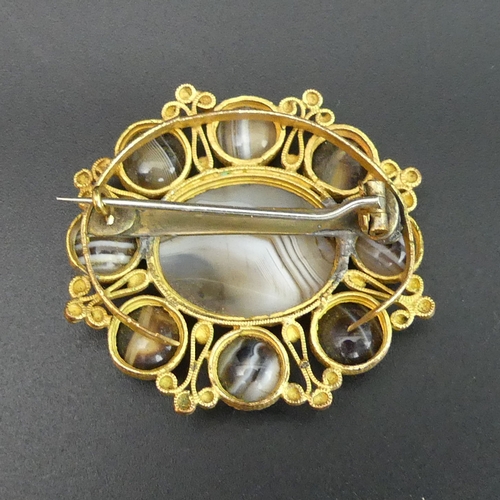 127 - A Victorian yellow metal (un-tested) banded agate brooch. 11.9 grams. 40 mm x 35 mm. UK Postage £10.