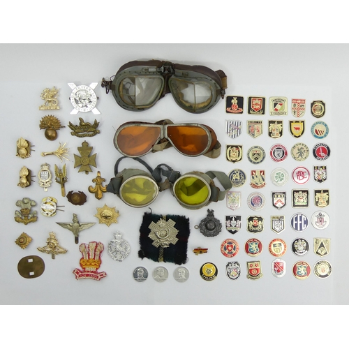 244 - A tin of army and other badges along with three pairs of flying goggles. UK Postage £12.