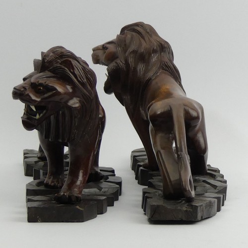 290 - A pair of early 20th century Japanese carved hardwood lions on stands. 28 cm long. UK Postage £14.