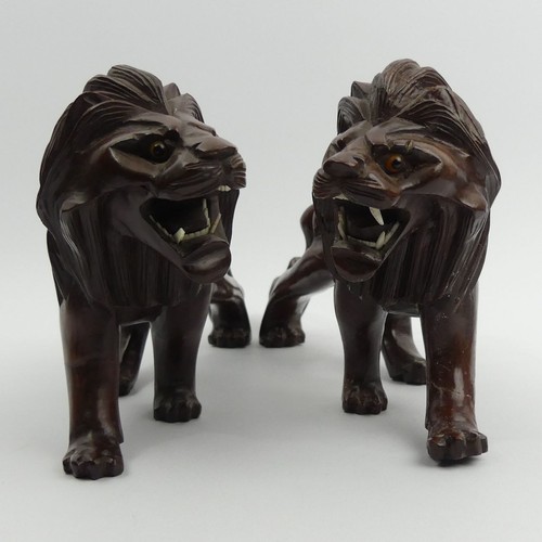 290 - A pair of early 20th century Japanese carved hardwood lions on stands. 28 cm long. UK Postage £14.