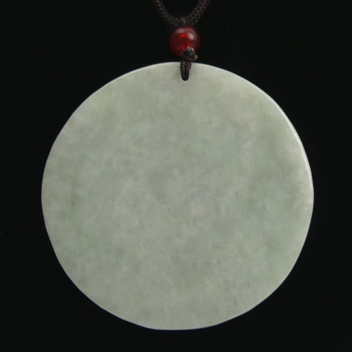 110 - Chinese celadon carved jade pendant with a tiger design on cord, 50mm in diameter.