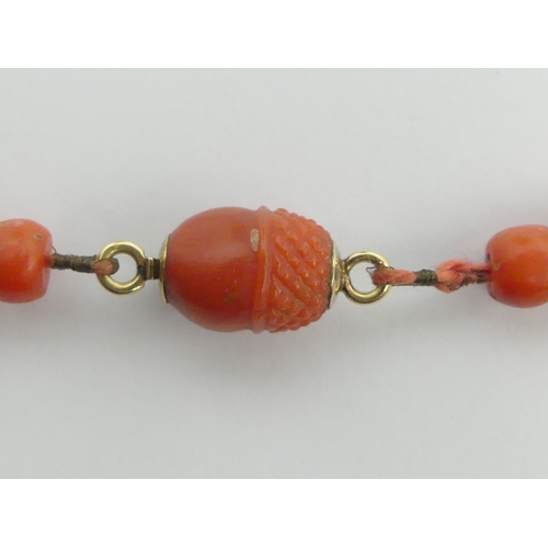 118 - Coral bead necklace with a carved acorn design clasp, 14.9 grams, 29cm.