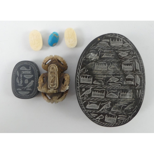 241 - A box of various uncut gemstones and carved scarab items.